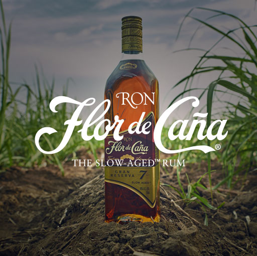 A bottle of flor de cana is sitting in the grass.