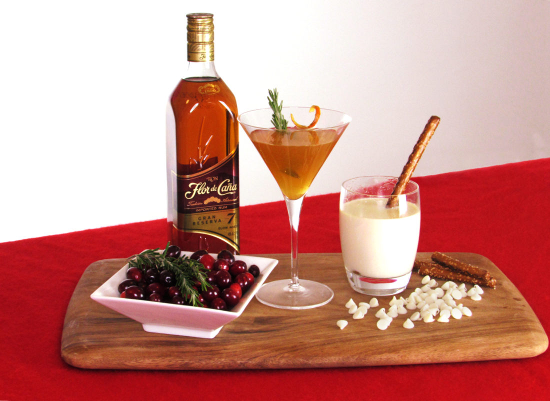 A tray with two glasses of liquor and some cherries.